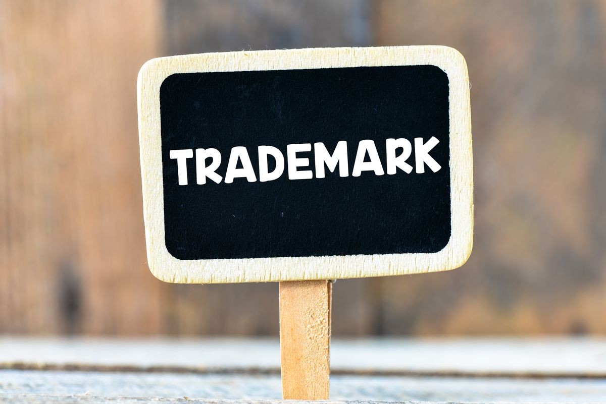Trademark / Trademark handwritten with white chalk on a blackboard on a wooden background